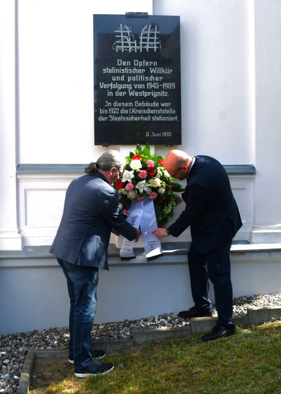 Landrat Christian Müller (r.) und der stellvertretende Kreistagsvorsitzende Siegbert Winter legten an der Erinnerungstafel für die Opfer des Stalinismus einen Kranz nieder. Foto: Bernd Atzenroth / Landkreis Prignitz
